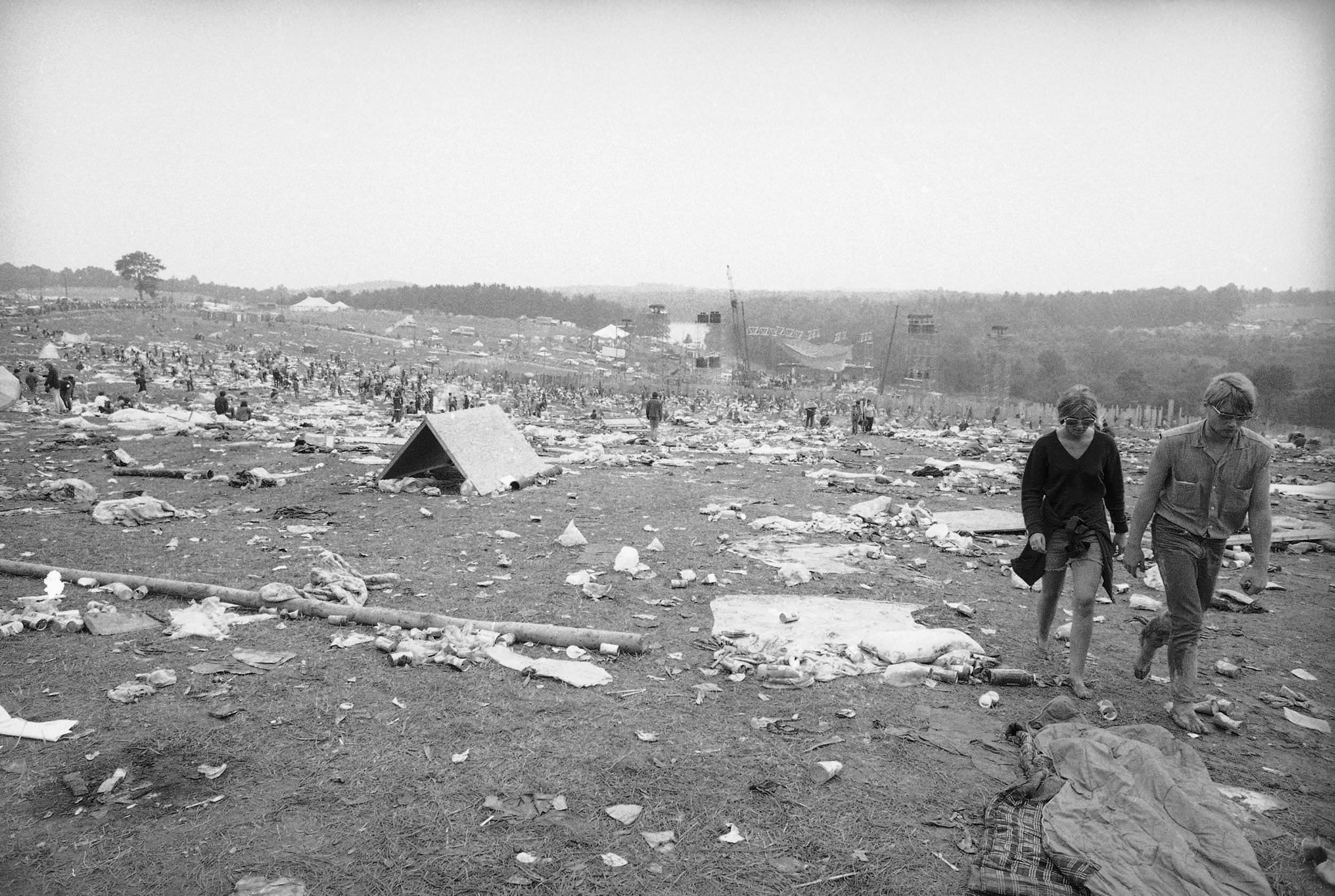 People linger around after the massive Woodstock Festival had ended in New York State, US in 1969. The concert was for 3 days, with up to 400,000 people attending. It was the biggest event of its kind at the time, but it was also poorly organized for the amount of people who attended. Most slept outside, in muddy conditions caused by rain. The dairy farm it was held on was utterly trashed, with it taking months to clean up. People bathed in a small stream nearby, or not at all. Some brought their children, even though heavy drug use was all over the grounds.