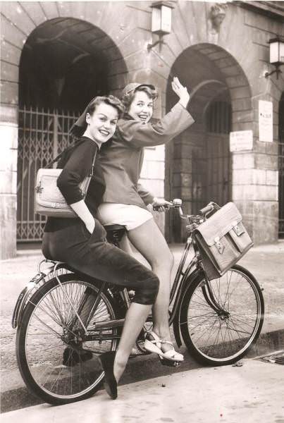 These schoolgirls are cycling home to change their clothes because tight-fitting slacks, pedal-pushers, and shorts had been banned in their school. (West Berlin, 1953)