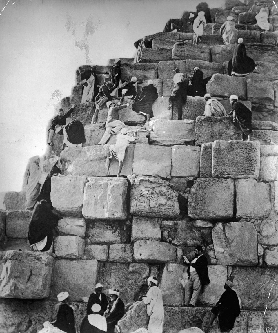 Tourists being assisted by their guides as they climb one of the Pyramids at Giza in the 1890s. Tourism at the Pyramids is thousands of years old, with people from the empires of Macedon, Rome, French, British and many more coming to Egypt to see them. They climbed them, took pieces, and this was before the sites were even excavated. Eventually, in the 1980s Egypt stopped people from climbing them, as such wear and tear was causing significant damage to the outsides of the Pyramids. It can be possible to still do so, perhaps with a pass for a fee, but not freely and easily as it was before the restrictions.