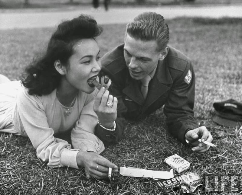 An American soldier shares cigarettes and chocolate with his Japanese girlfriend outside of Tokyo, Japan in 1946. The soldier is in fact violating restrictions on giving Japanese civilians such rations. Many Americans stationed in Japan for the 10 years of the US occupation after WWII integrated with the locals. Around 2.3 Million Japanese soldiers died in the war, with another 326,000 wounded. Not only that, all surrendering soldiers were not allowed to return to a daily life so quickly. Over 4.4 percent of the Japanese population died, with their entire government, economy, and infrastructure broken down. This left many families, especially young women, no way to support themselves. But the hundred of thousands of American men stationed in the country had access to necessities which made such relationships commonplace and totally acceptable across the country.