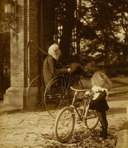An old man riding a bike passes a young girl riding on hers.