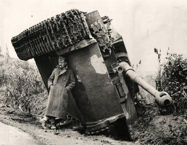 British soldier hiding from the rain under the German tank “Tiger” during World War II, 1944.