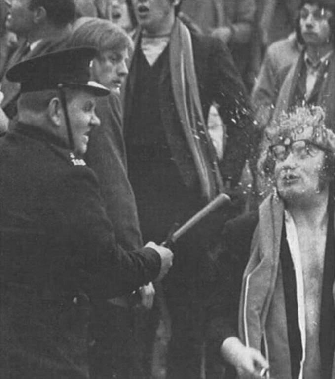 Policeman uses baton on  football supporter after a game, 1971.