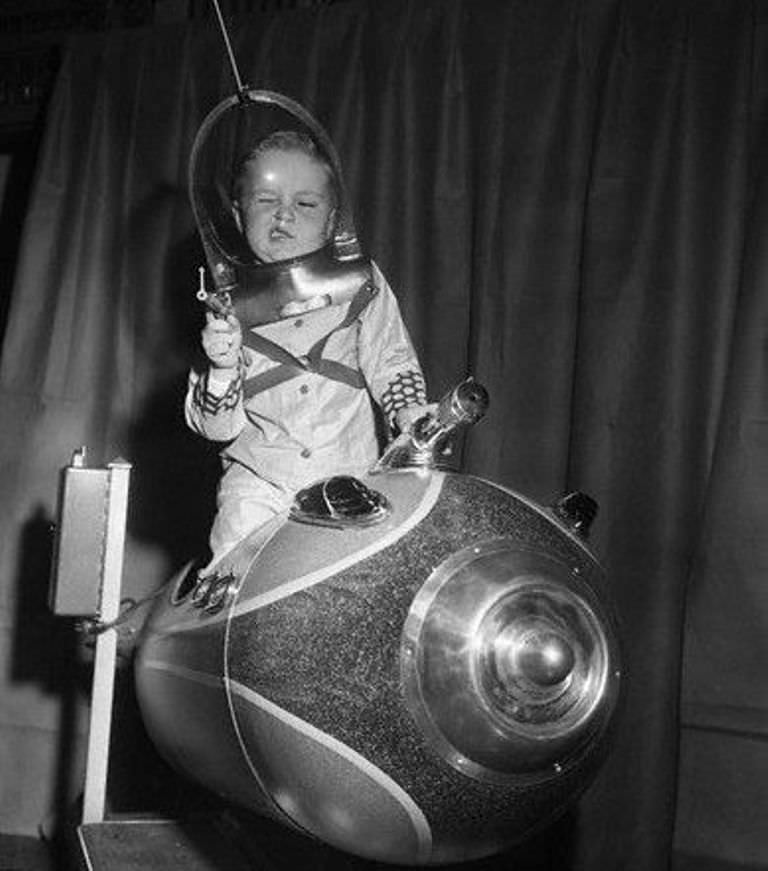 Kid playing on a coin operated spaceship at the American Toy Fair in 1953.