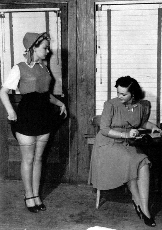 18 Year old Ruth Oliphant being inspected and coached by Mrs. Sivils on how to be a car hop girl (a waitress to drive in restaurants) in Houston, Texas in 1940. Mrs. Sivils coached the girls in diction, deportment and the importance of laughing at customers' jokes.