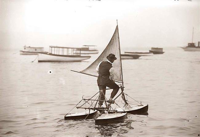 A man operating a tricycle sailboat in 1922.
