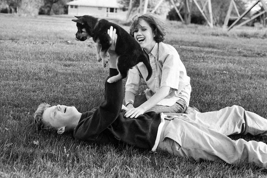 Molly Ringwald and Anthony Michael Hall play with a puppy during a break in filming on the set of The Breakfast Club.