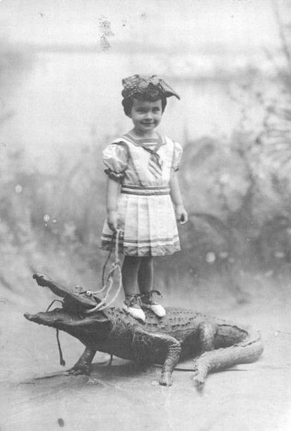 A girl stands on an alligator (labelled a pet but looks stuffed) in Louisiana, US in 1927.