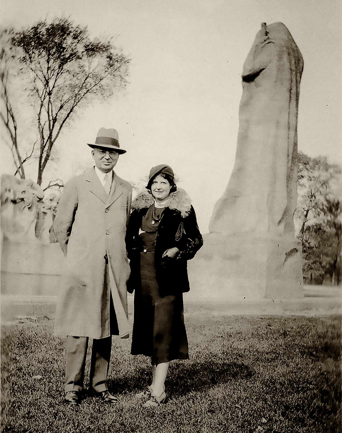 A couple stands near a statue in an unknown location, 1951.