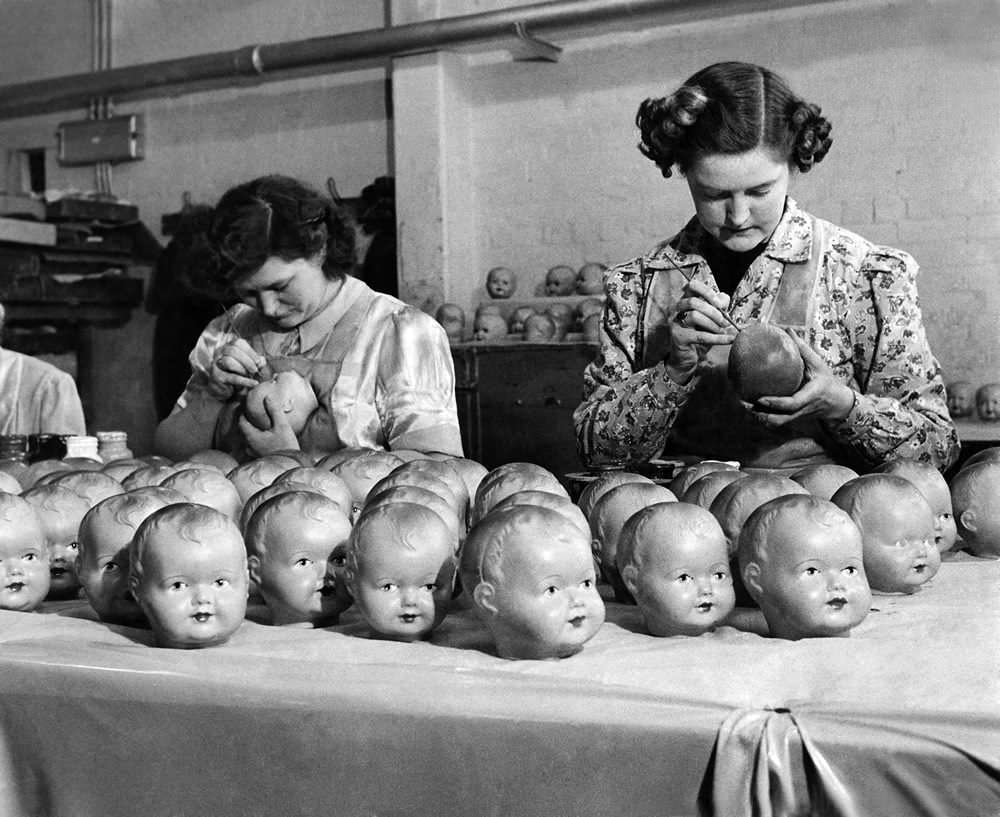 Painting the eyes and lips on dolls in a factory in the US, 1950.