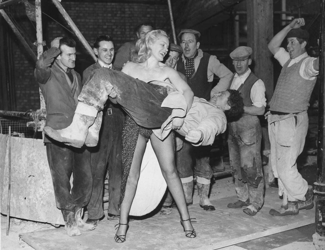 (Joan Rhodes lifting a worker up with ease to every ones amazement in 1958). She started in the 1950s when she began do cabaret performances often showing her grace then surprising the audience with her immense strength. She did this through London as she grew in popularity. She even lifted giant Ted Evans who reportedly weighed 480 pounds.