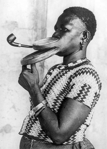 Madame Gustika of the Duckbill tribe (nickname for her native African tribe) smokes a pipe while doing a freak show tour in the US, 1930.