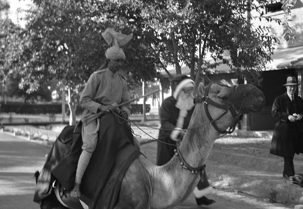 Santa Claus walks next to a soldier on a camel in India, 1930.