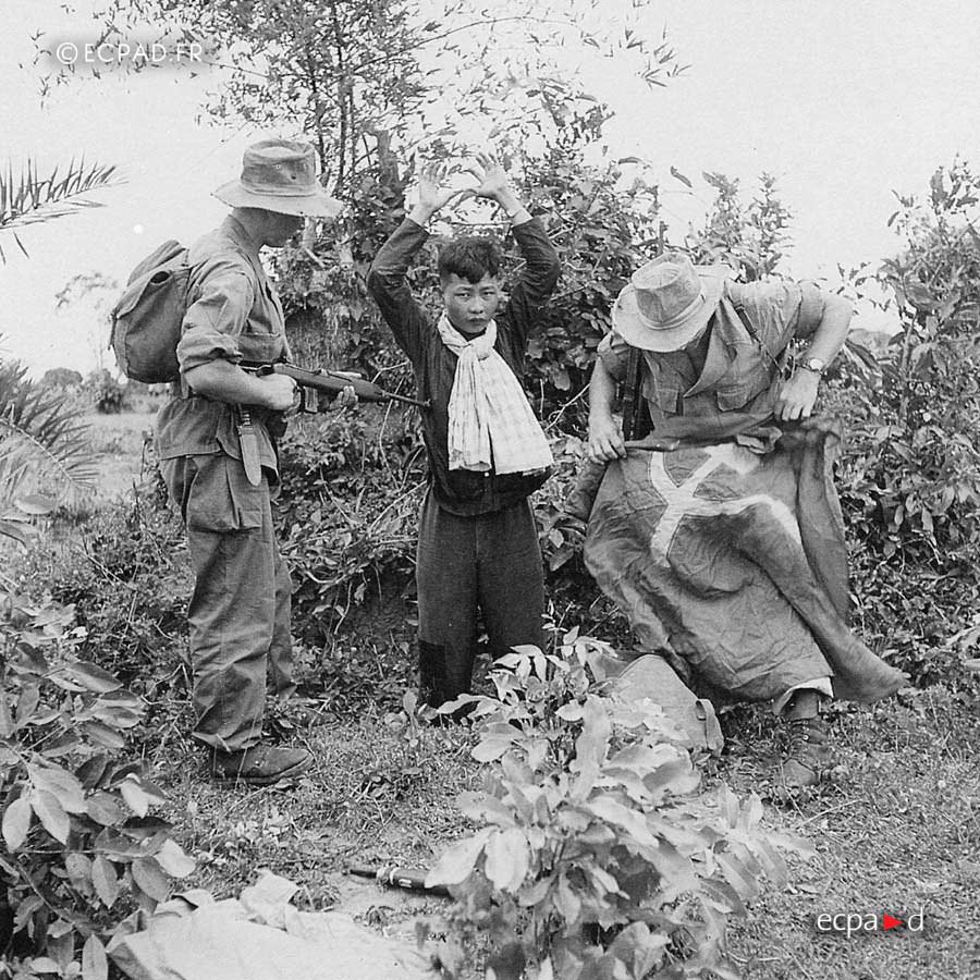 A Viet Minh rebel captured by two legionnaires during Operation Rouleaux in French Indochina, 1950.