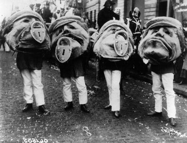 Giant head costumes with padlocks on the chin at the carnival at Mainz, Germany in 1912.