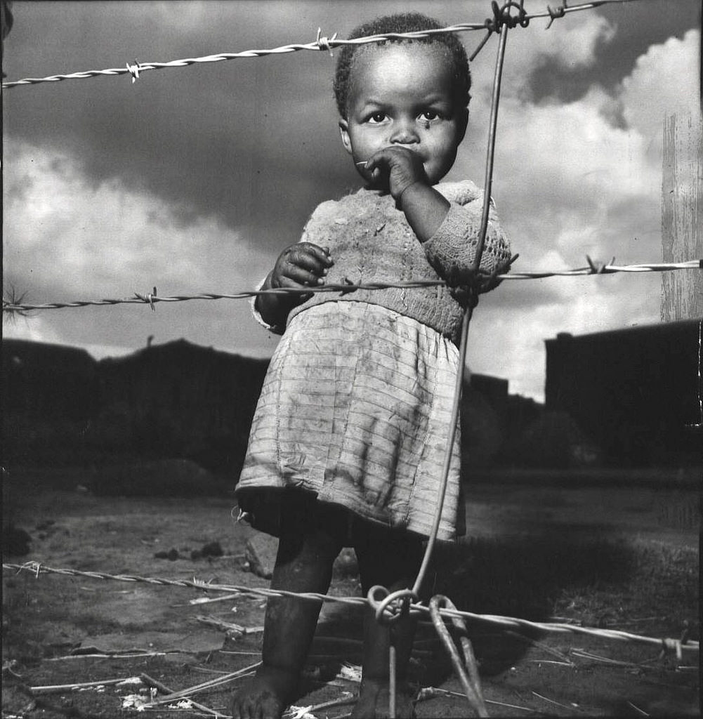 A child stands on a blocked off section setup to ensure a racial divide in Johannesburg, South Africa in 1950.