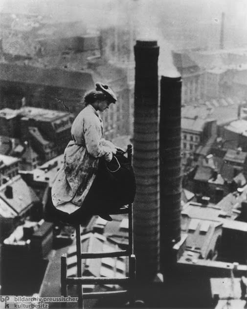 A female mason worker perched high on a rooftop in Berlin, Germany in 1910.
