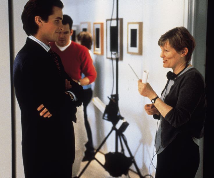 Christian Bale and director Mary Harron laugh between filming American Psycho in 2000.
