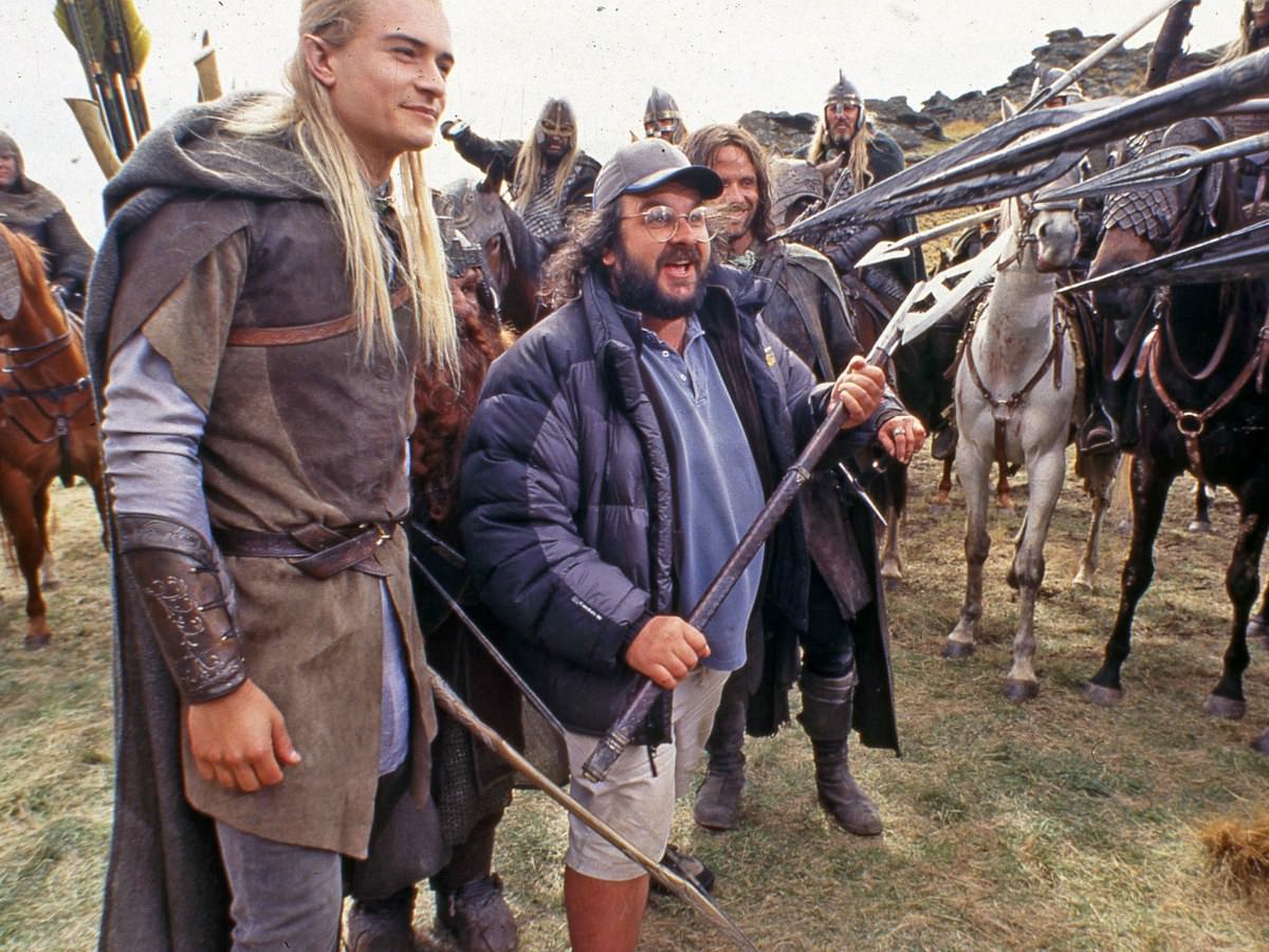 Peter Jackson shows John Rhys-Davies stand in how he wants him in a scene, while Orlando Bloom and Viggo Mortensen laugh, while filming The Lord of the Rings: The Two Towers in 2002.