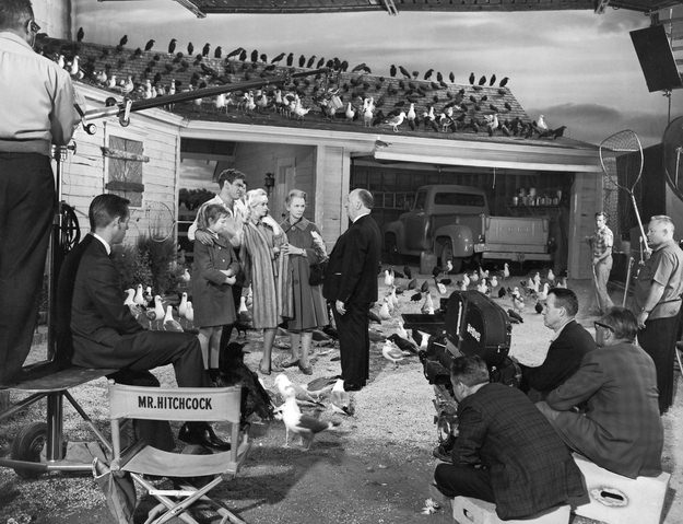 Alfred Hitchcock (center black suit) prepares everyone for a scene in The Birds in 1963.