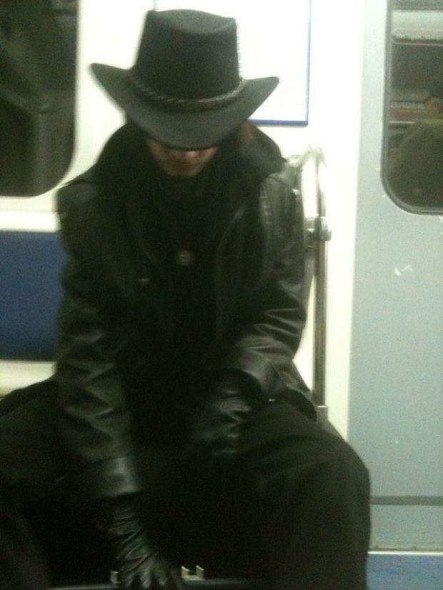 Man in black leather coat, black gloves, and black hat.