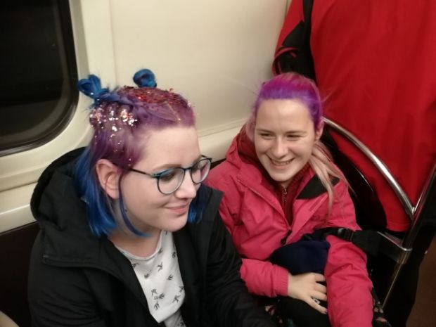 Woman with colored hair and sparkles sitting next to woman with colored hair