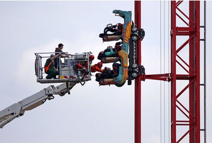 A man getting rescued from a broken rollercoaster.
