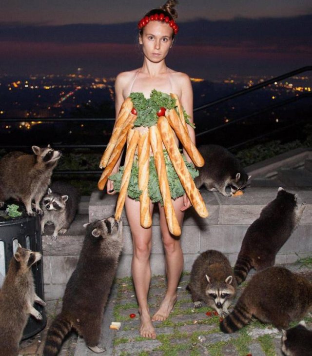 woman wearing baguettes and lettuce surrounded by raccoons