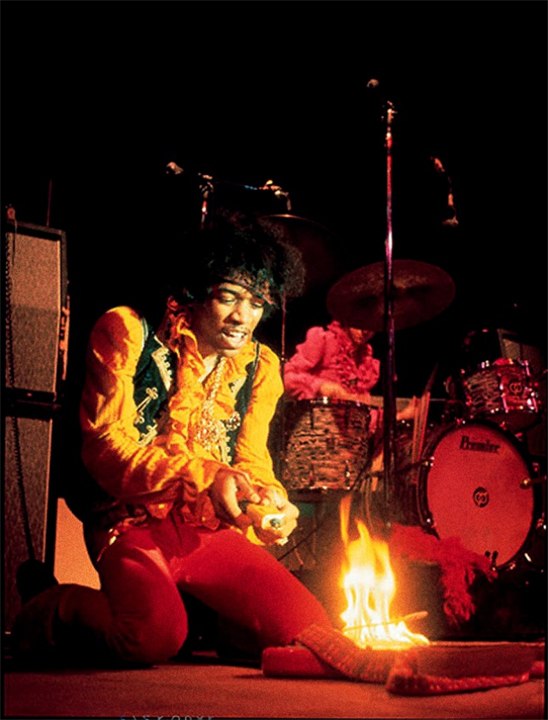 Jimi Hendrix in London, 1967. He did not anticipate that England is cold and has lots of rain and had to improvise to keep warm. Here he makes a fire using his guitar, later he kept bodyheat by hugging four naked models.