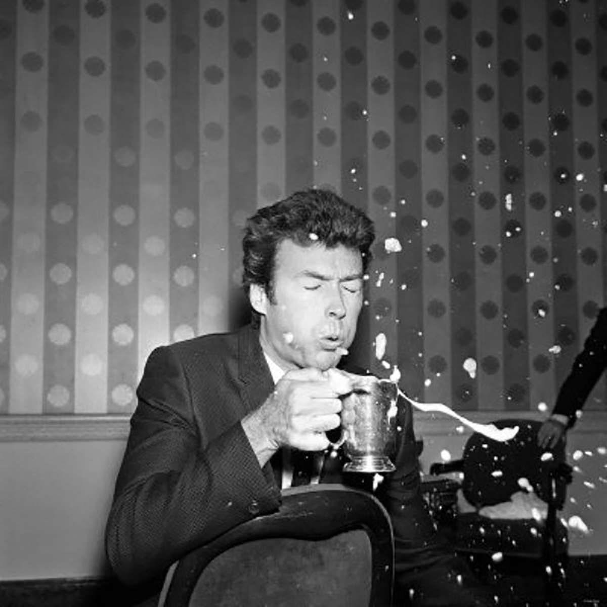 Clint Eastwood blowing the foam off his beer all over, early 1960s.