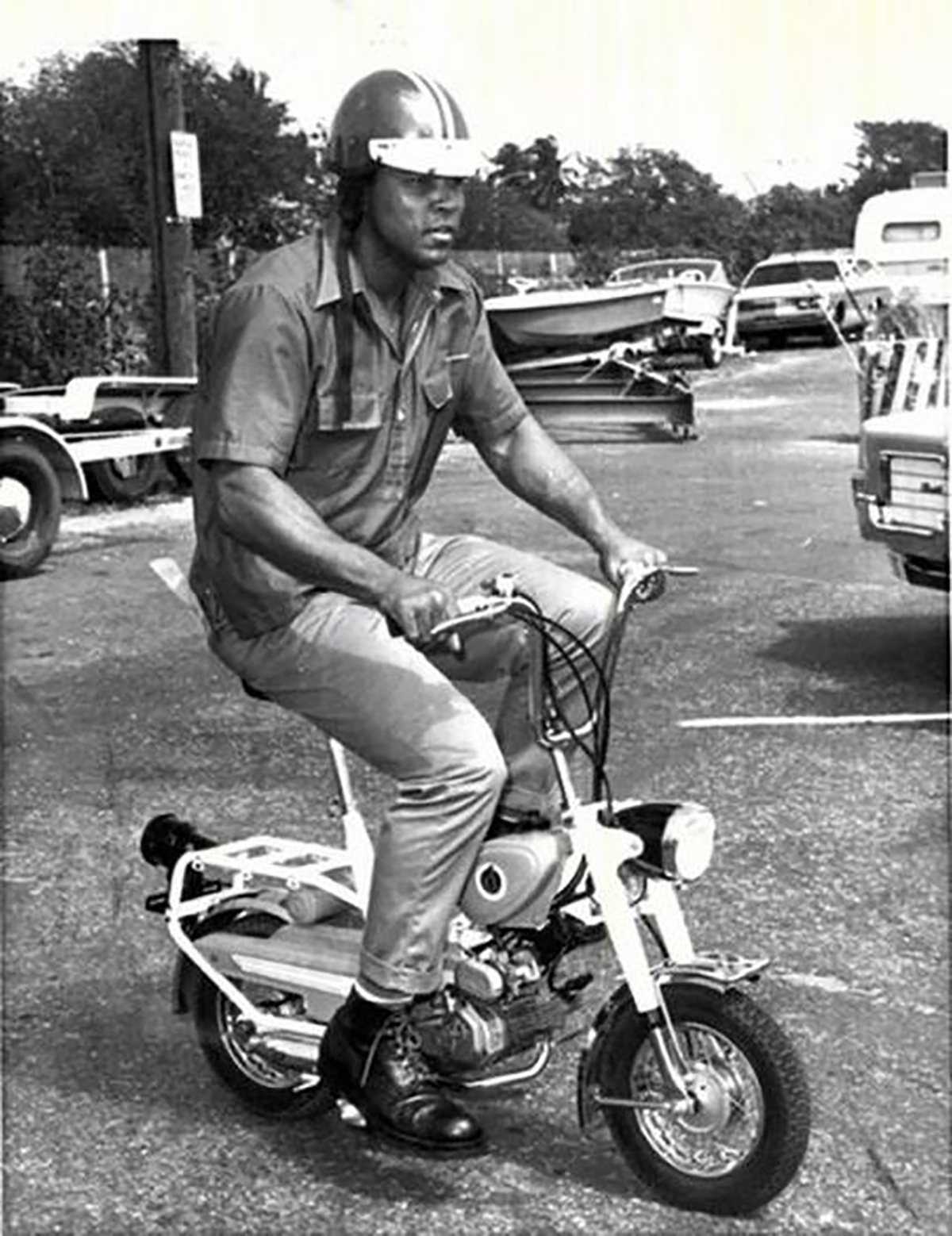 Cassius Clay riding a small scooter in the 60s.