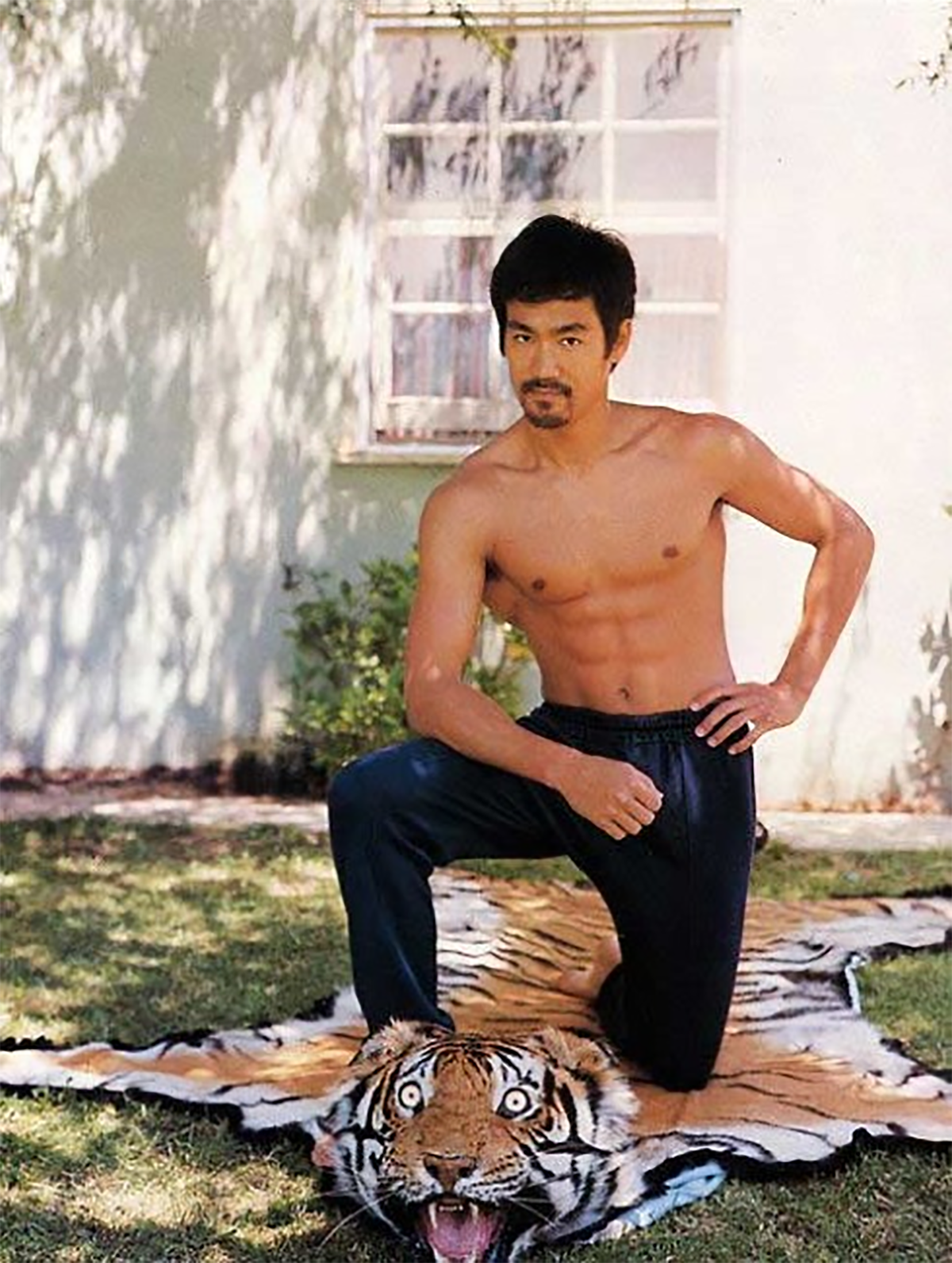 Bruce Lee posing on a tiger rug in front of his home for a magazine shoot in the early 1970s.