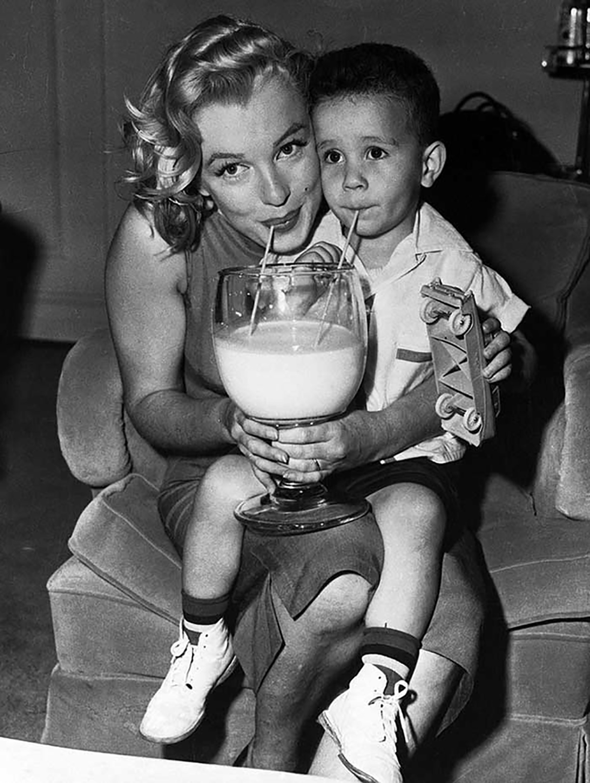 Marilyn Monroe taking a picture with a child drinking milk as part of the Milk Fund For Babies charity program she sponsored in 1955.