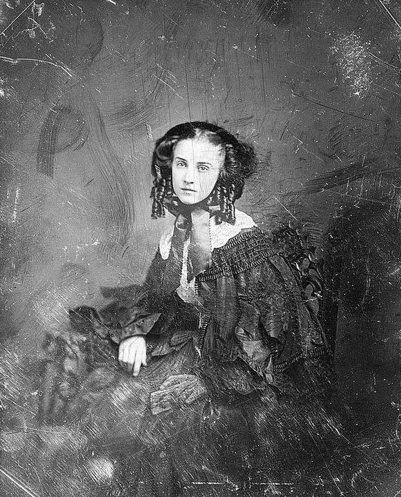 Portrait of young unknown woman in black holding a photo of a man