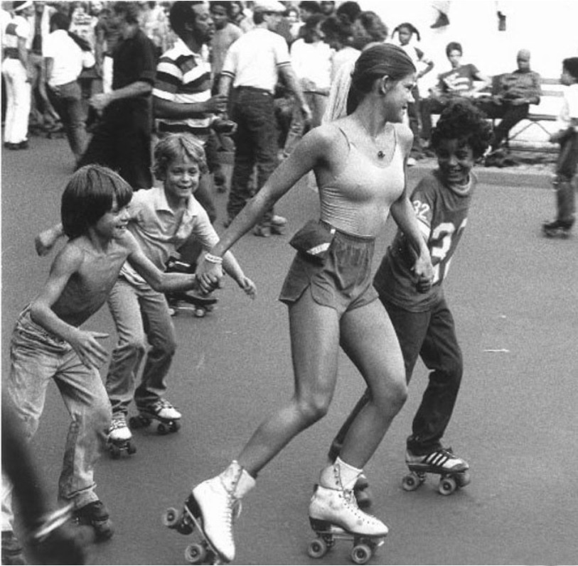 Pretty roller girl skating with kids, ca. 1970s.