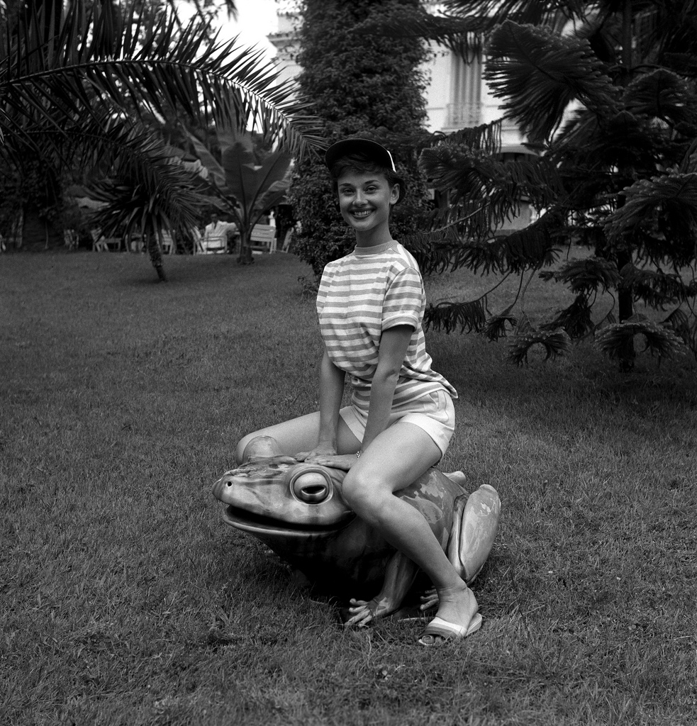 Audrey Hepburn sitting on a large frog, 1960s.