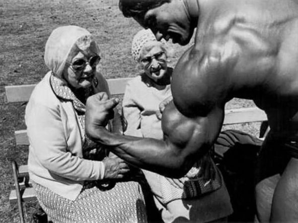 Arnold Schwarzenegger flexing for two old ladies in ~1970.