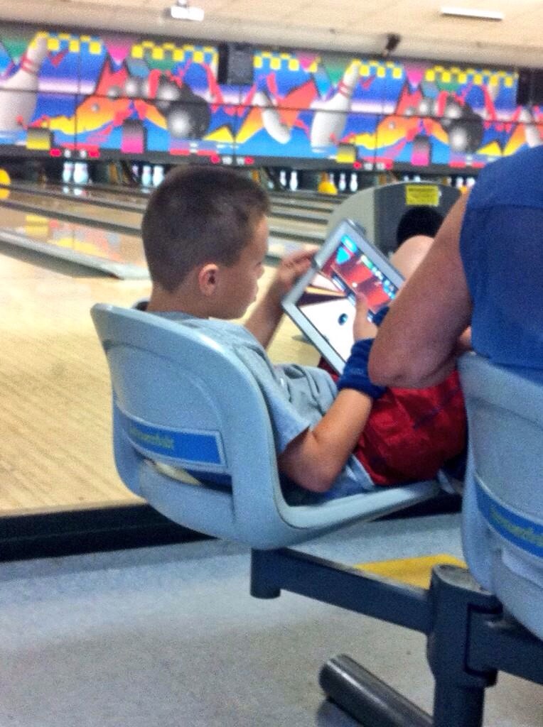 kid playing bowling game at bowling alley
