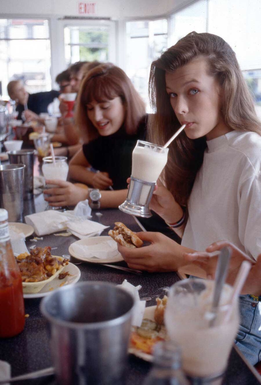 Milla Jovovich having a burger and milkshake at Johnny Rockets on Melrose in Hollywood (1987).