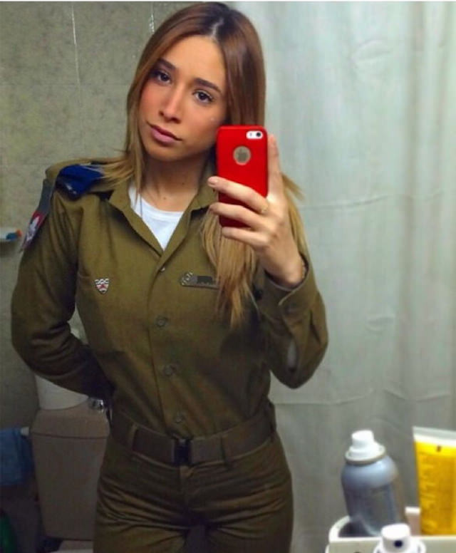 Kim Mellibovsky taking a mirror selfie while in uniform with an iphone with a red cover