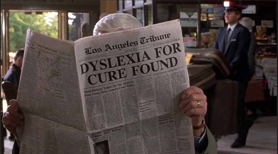 Funny picture from a movie in which someone is reading a newspaper that says Dyslexia For Cure Found