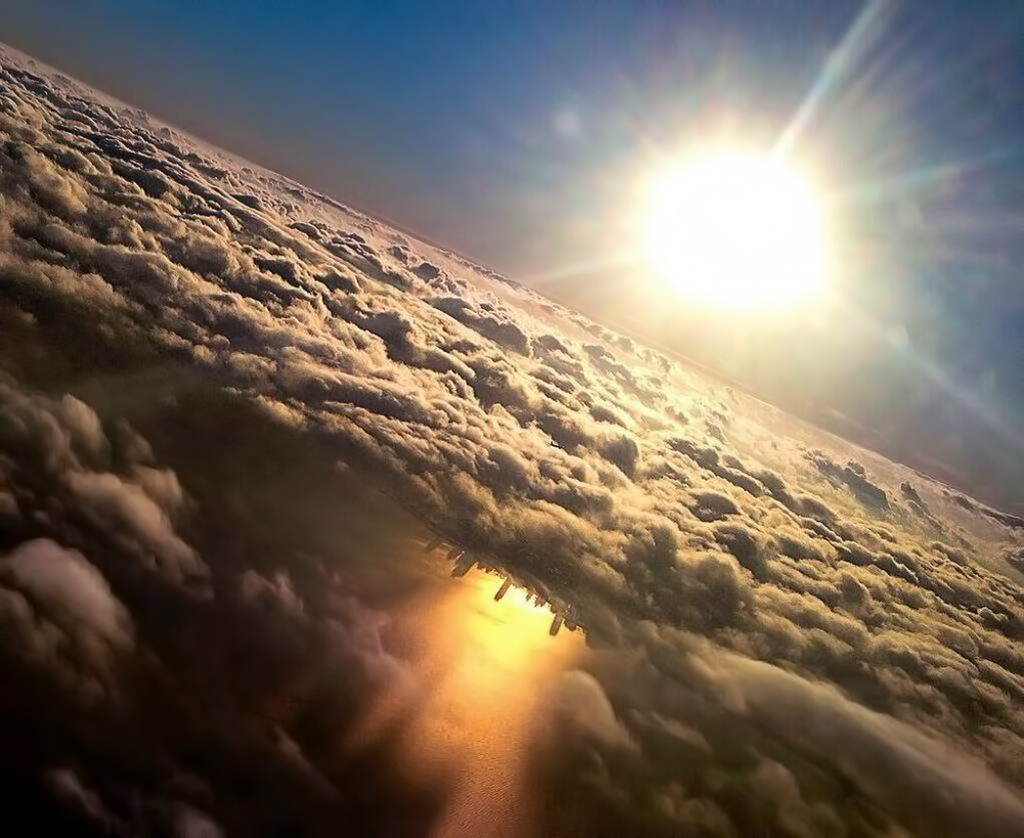 Cool picture of the sun above the clouds and the reflection of the city below in the water.