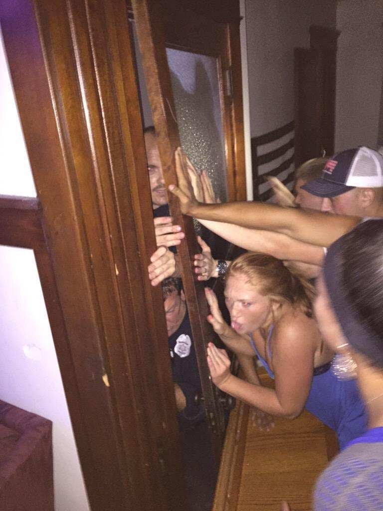 Party-goers pushing closed a door to stop the cops from coming in.