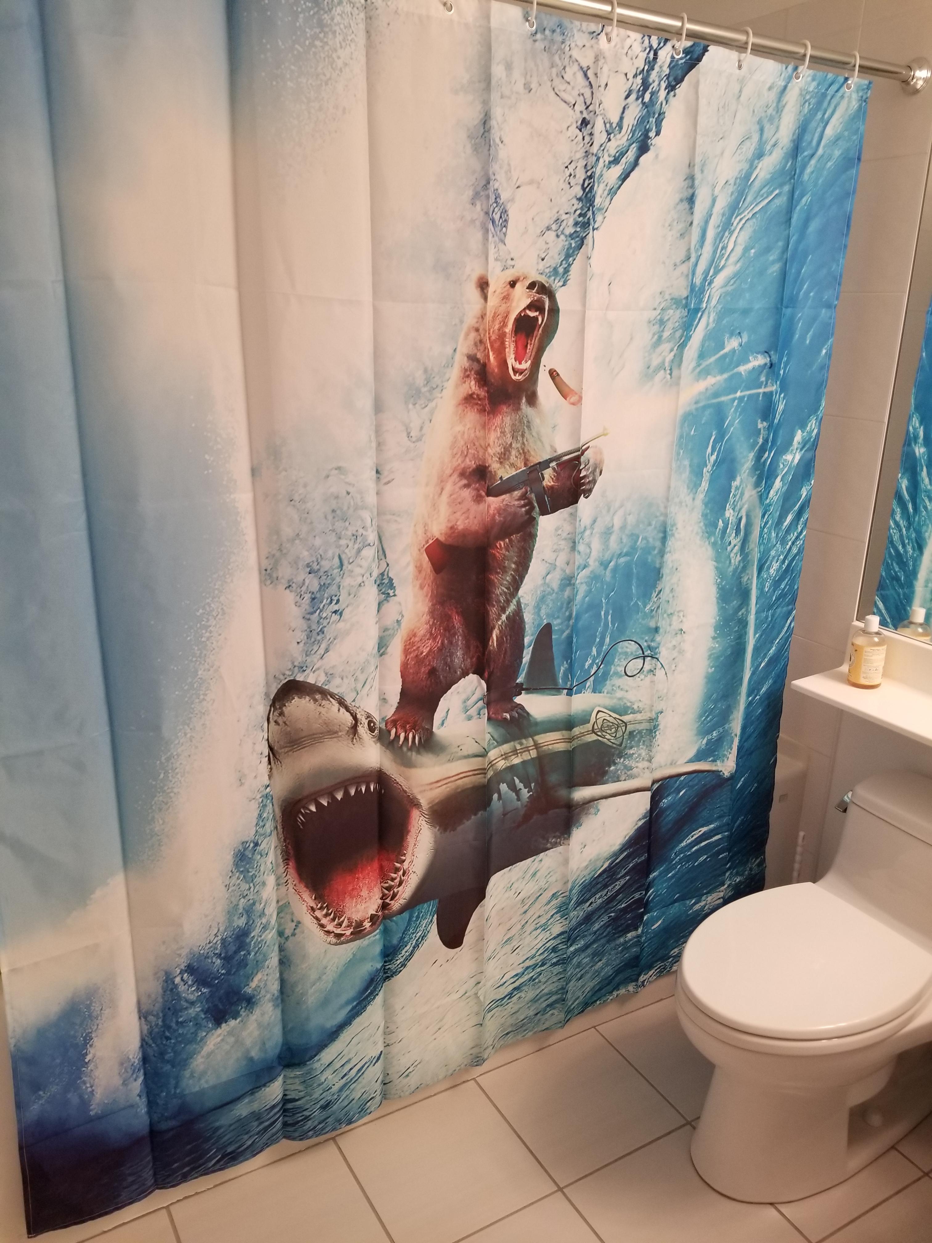 Awesome picture of a shower curtain with a bear riding a shark while firing a machine gun.