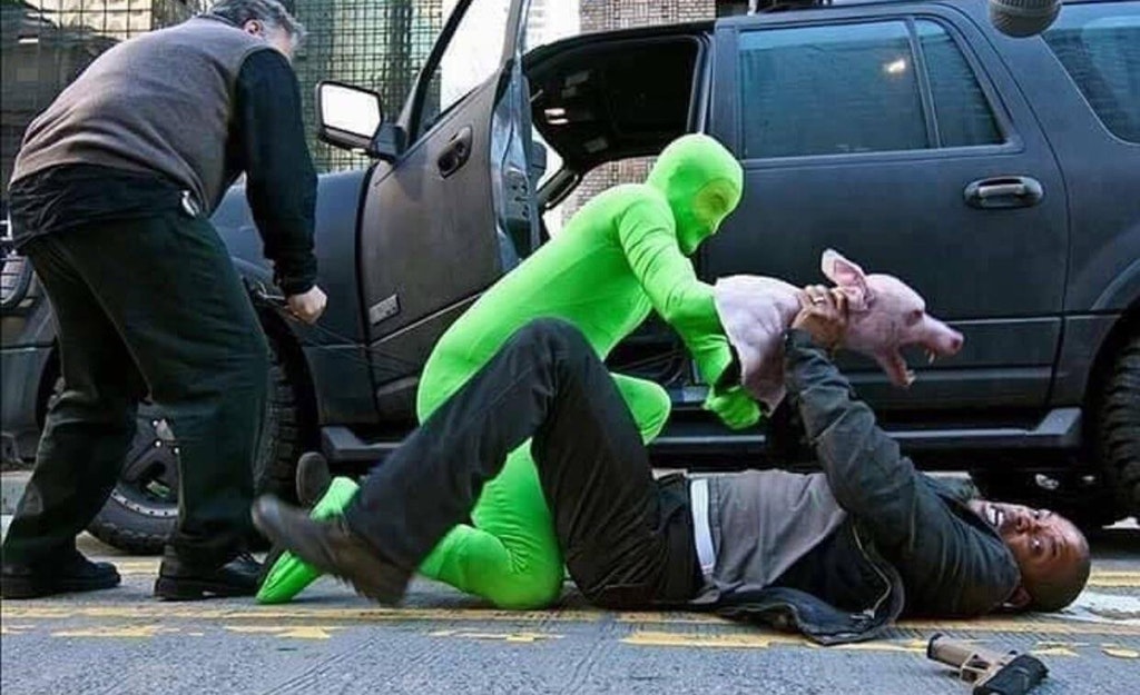 Man wearing green suit holding a puppet of a rabid wild dog as it fights Will Smith in the shooting of the scene fro I Am Legend.