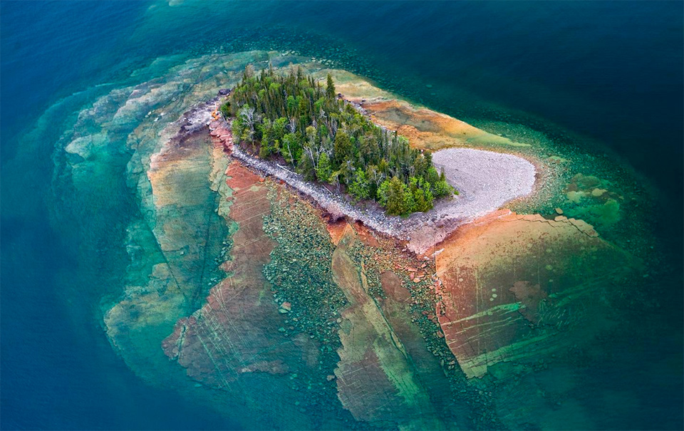 Awesome island with a forest on most of the landmass and a visible outlying shallow areas.