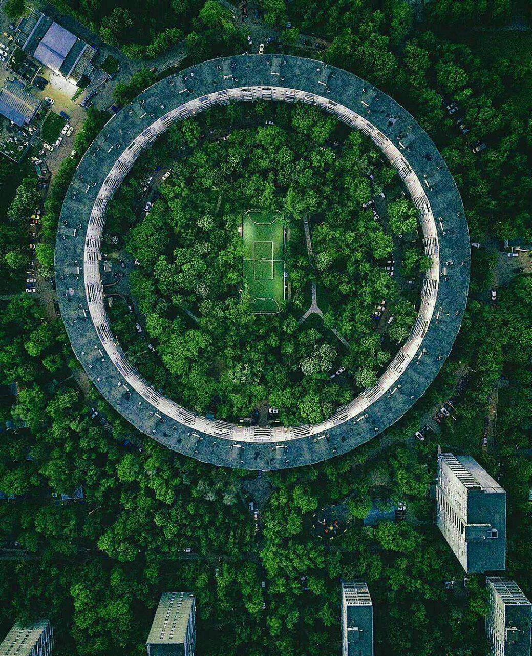 Aerial photograph of a tennis court in the middle of a circular building surrounded by trees