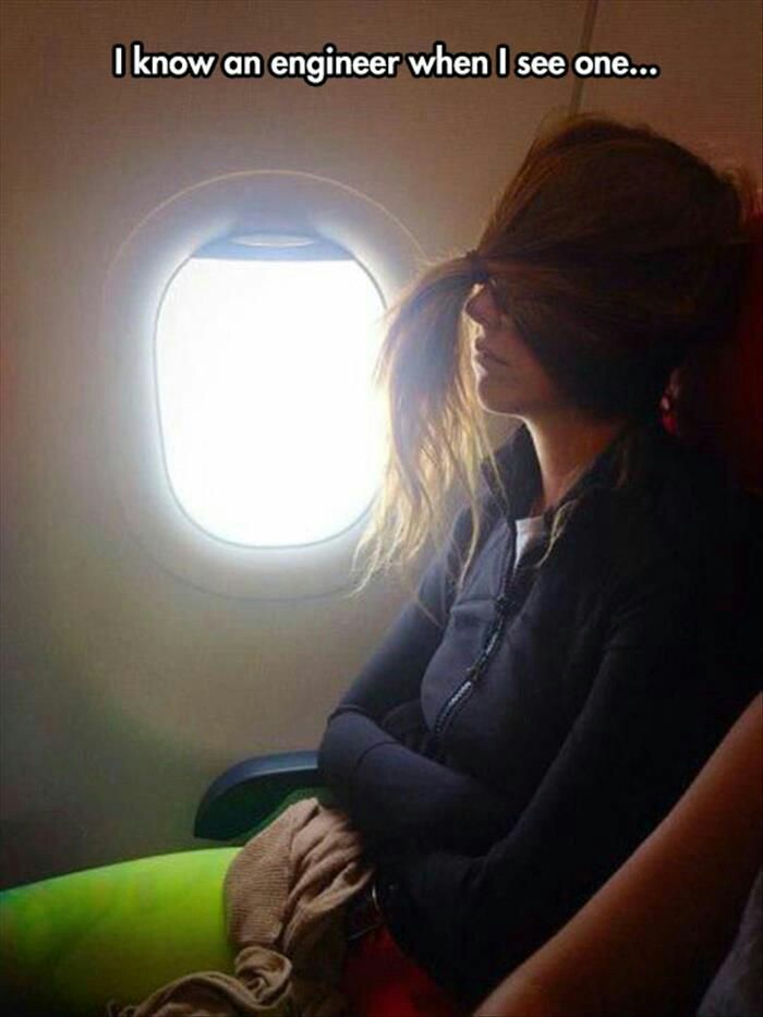 Woman on an airplane who is clearly an engineer with her hair tied in the front to block out the light.