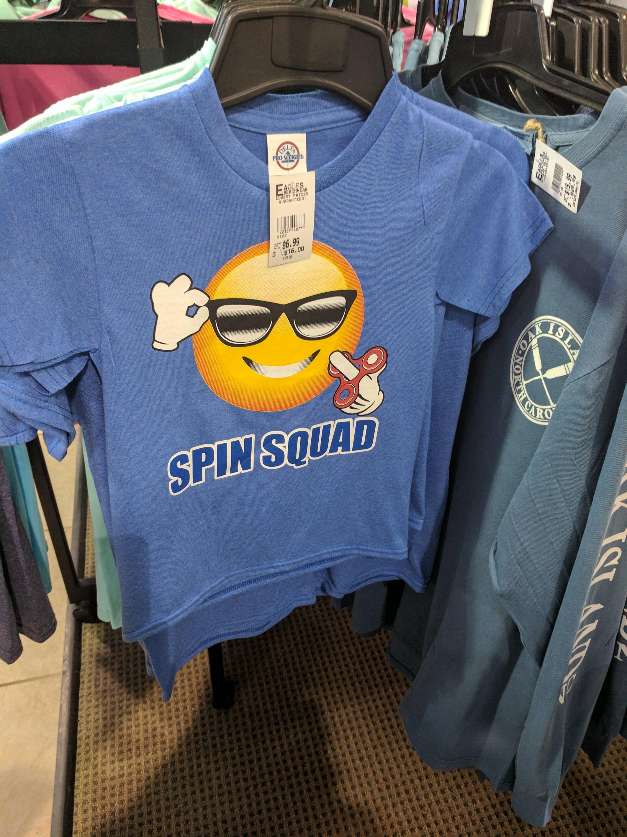T-shirt of an emoji with sunglasses spinning a fidget spinner.