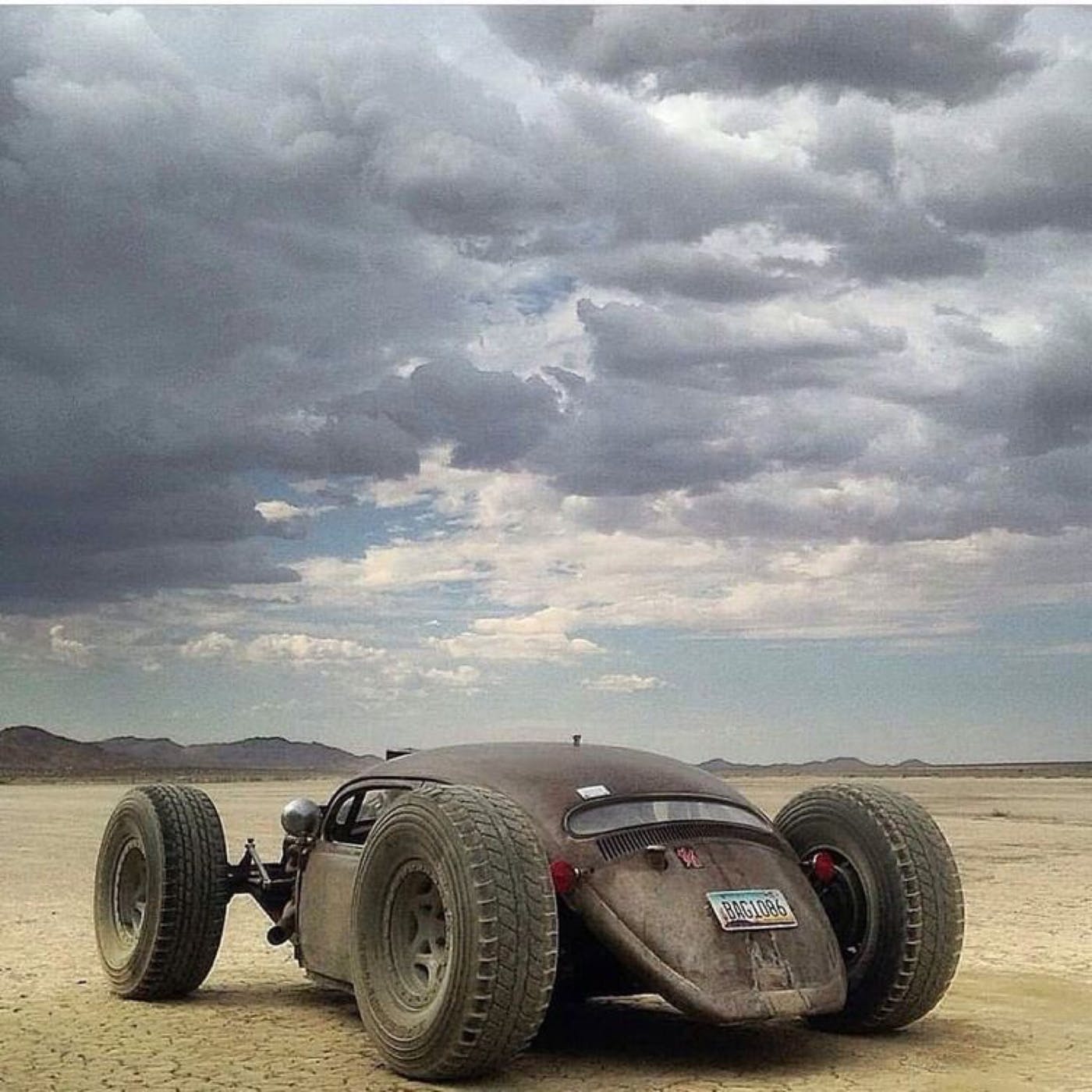 Awesome looking dune buggy in the desert with dramatic clouds.
